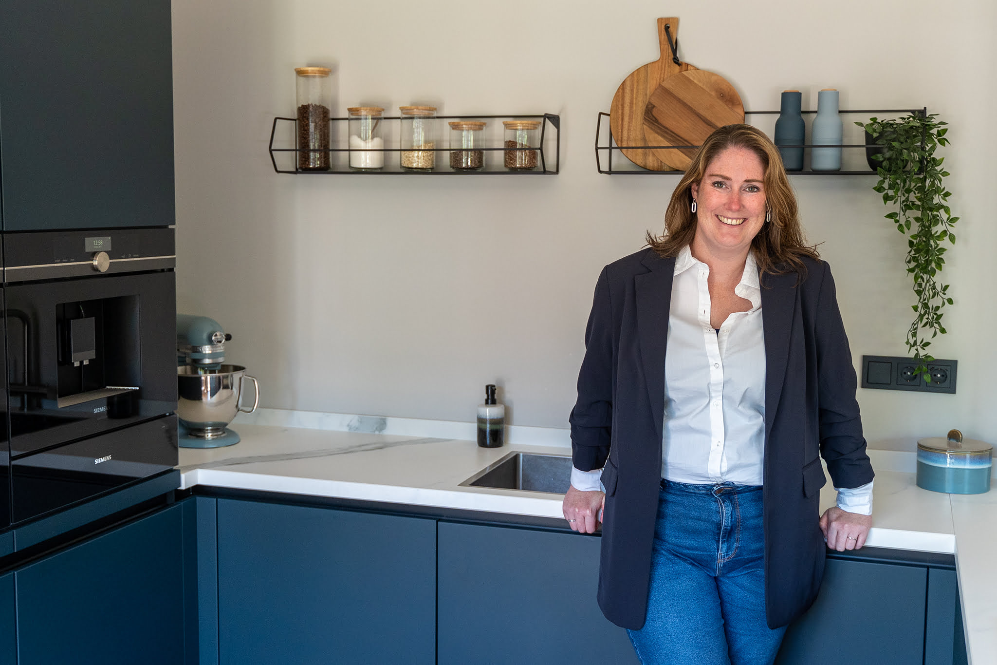 Daniëlle Cortjens staand in moderne donkerblauwe keuken.