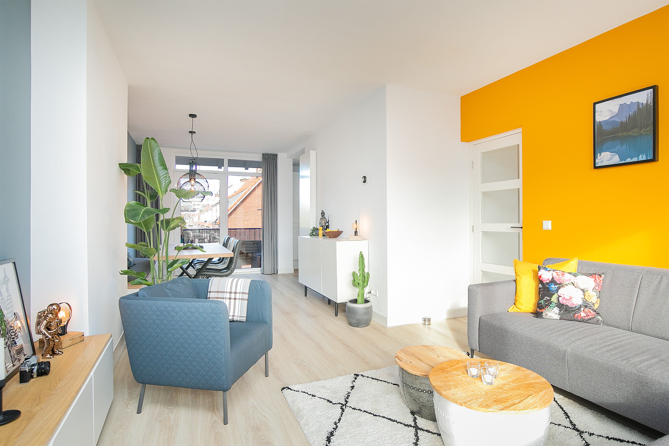 Scandinavische stijl woon- en eetkamer met licht eiken vloer, moderne meubels en planten. Renovatie appartement in Voorburg.