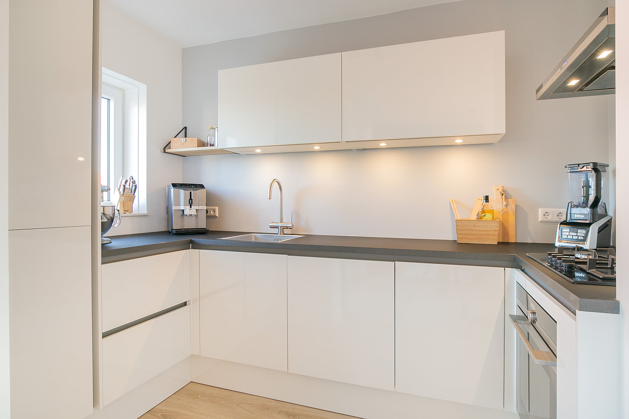 Moderne witte keuken met antraciet werkblad en voorzien van alle nodie apparatuur. Renovatie appartement in Voorburg.